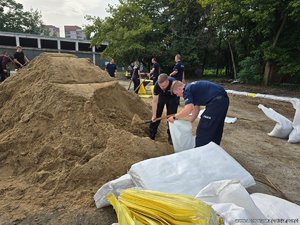 policjanci kopią piasek i wsypują go do worków