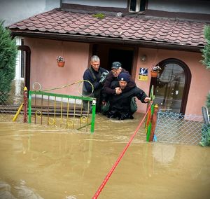 zalany dom, przez drzwi tego domu policjant wynosi na plecach seniora