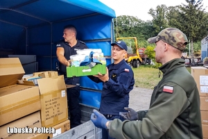 Policjanci rozładowywują dary z ciężarówki.