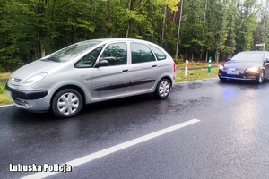 Osobowy citroen stoi na jezdni a za nim nieoznakowany policyjny radiowóz - widok z boku.