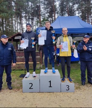 Na podium laureaci. Obok po jednej i drugiej stronie podium stoi policjant.