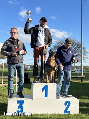 Trzej zawodnicy na podium zawodów kynologicznych.