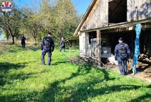 Policjanci przeszukujący opuszczone zabudowania.