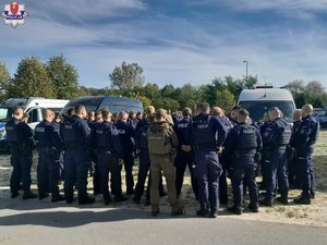 Grupa policjantów i innych osób biorących udział w poszukiwaniach podczas odprawy.