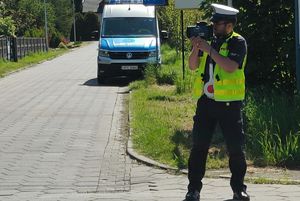 policjant ruchu drogowego patrzy w miernik prędkości.