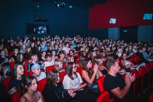 Młodzież i opiekunowie siedzący na widowni w domu kultury w Będzinie.