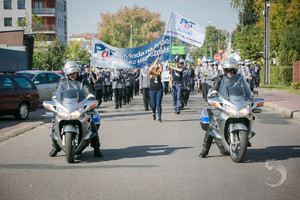 Policyjna eskorta na motocyklach prowadzi przemarsz młodzieży.