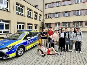 Uczniowie z policjantami pozują przy radiowozie.