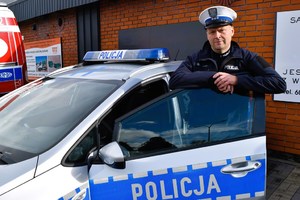 Policjant stoi przy radiowozie.