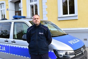 Policjant stoi przy radiowozie.