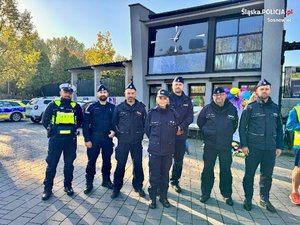 siedmiu umundurowanych policjantów stoją przed budynkiem.