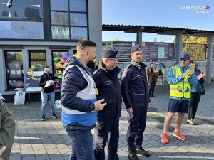 dwoje policjantów i cywil stoją na ulicy.