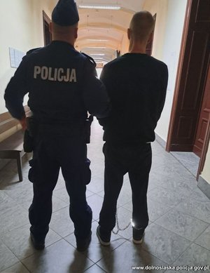 Policjant prowadzi zatrzymanego.