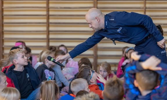 policjant daje mikrofon chłopcu