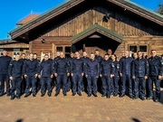 Zbiorowe zdjęcie umundurowanych policjantów z Zastępcą Komendanta Głównego Policji i Zastępcą Komendanta Wojewódzkiego Policji w Białymstoku. W tle widać budynek.