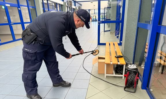 Policjant sprawdza ławkę specjalistycznym sprzętem