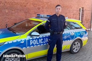 policjant stoi przed radiowozem.