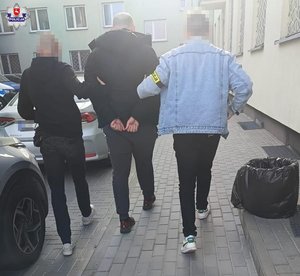 policjanci idą z zatrzymanym.