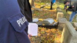 Policjanci dokonujący oględzin na cmentarzu.