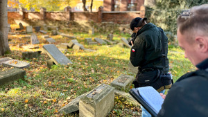 Policjanci dokonujący oględzin na cmentarzu.