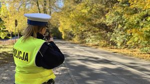 Policjantka stoi przy drodze trzymając fotoradar.