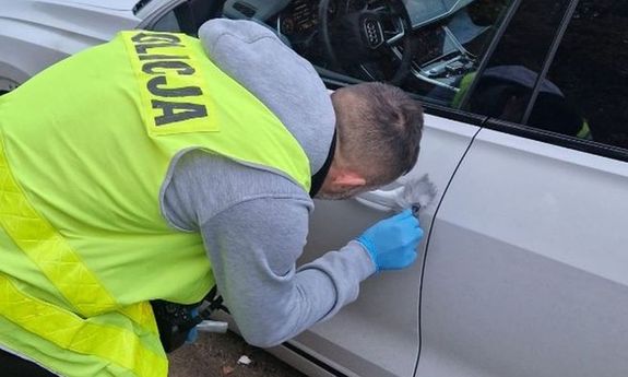 policjant ściąga odciski palców z klamki.