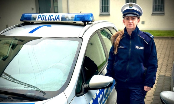 Policjantka stoi przy radiowozie.