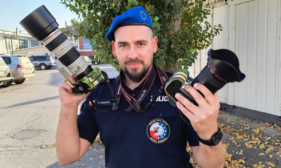 policjant pozuje z aparatami w rękach.