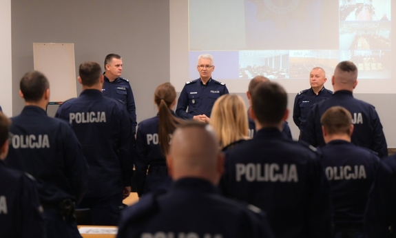 Grupa policjantów siedzących w ławkach podczas rozpoczęcia kursu aspiranckiego w katowickiej komendzie wojewódzkiej.