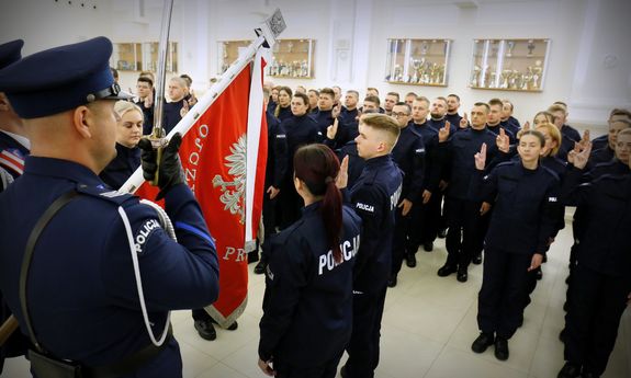 uroczystość ślubowania, w sali widać policjantów w mundurach ślubujących przy sztandarze