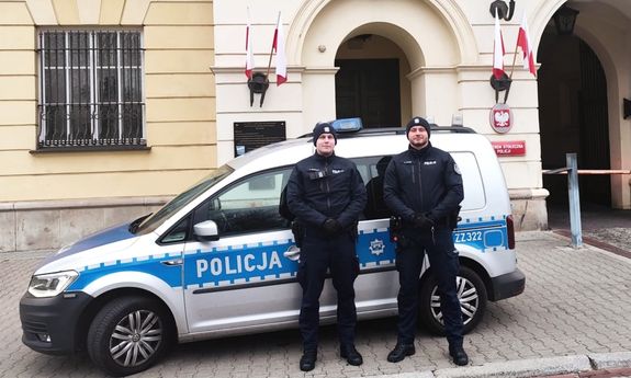 policjanci stoją przy radiowozie.