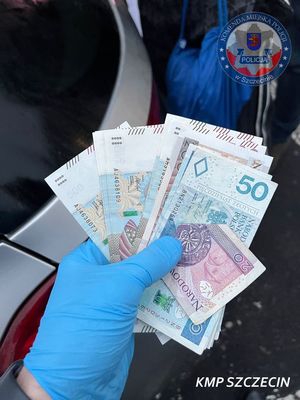 Banknoty trzymane w dłoni, na której założone są niebieskie lateksowe rękawiczki.