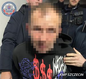 Na zdjęciu trzech policjantów prowadzi zatrzymanego mężczyznę.