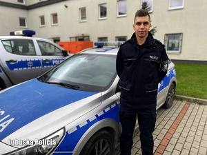 Na zdjęciu umundurowany policjant stoi przy radiowozie.