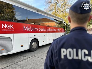 Policjant stojący przed krwiobusem.