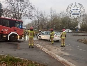 strażacy stoją obok rozbitych samochodów.