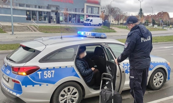 Policyjny radiowóz, policjanci i kobieta, której udzieli pomocy.