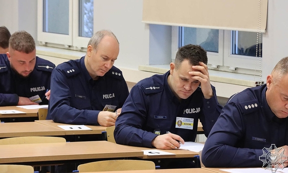 Policjanci siedzą w ławkach w trakcie rozwiązywania testu.