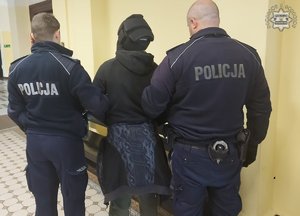 policjanci prowadzą zatrzymanego.