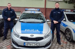 policjanci stoją przy radiowozie.