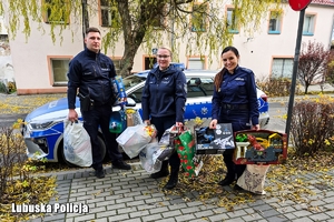 Na zdjęciu umundurowani policjanci z prezentami dla dziecka. W tle radiowóz.