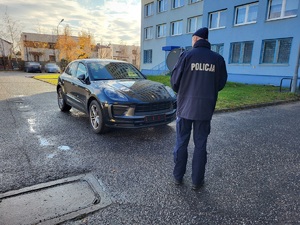 policjant stoi przed porsche.