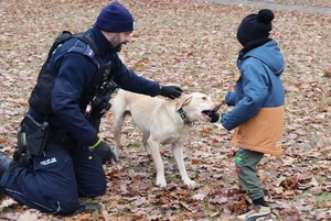 Policjant z psem policyjnym kuca przy dziecku.