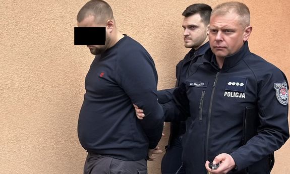 Dwaj umundurowani policjanci prowadzą zatrzymanego.