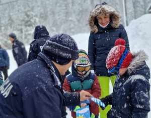 Policjant rozdaje dzieciom ulotki.