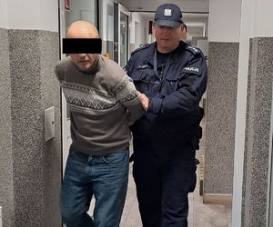 policjant idzie z zatrzymanym.