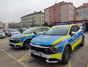 Dwa oznakowane radiowozy na parkingu Komendy Powiatowej Policji w  Dąbrowie Tarnowskiej.