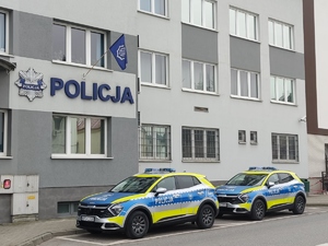 Dwa oznakowane radiowozy na parkingu Komendy Powiatowej Policji w  Dąbrowie Tarnowskiej.