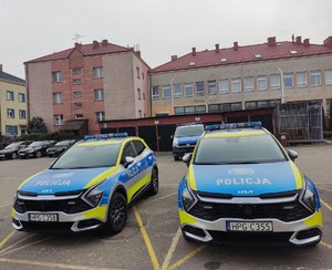 Dwa oznakowane radiowozy na parkingu Komendy Powiatowej Policji w  Dąbrowie Tarnowskiej.