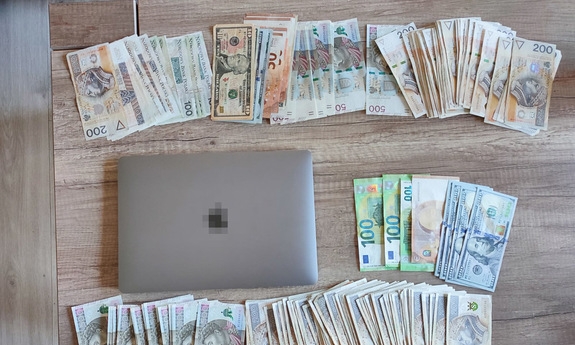 Na blacie leżą banknoty i laptop.